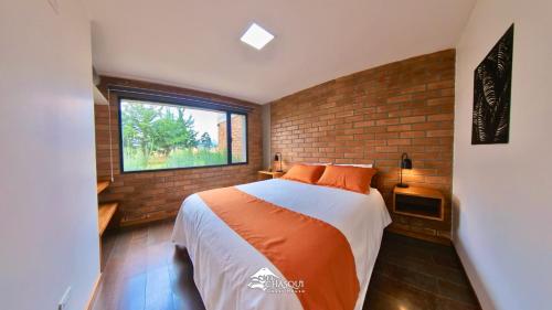 a bedroom with a bed and a brick wall at El Chasqui Guest House in Chasqui