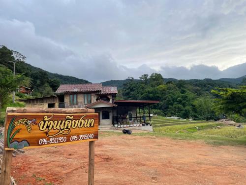 a sign in front of a building in front of a field at บ้านพักเคียงนา in Ban Sop Mae Klang