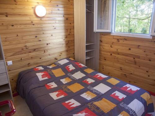 a bedroom with a bed with a quilt on it at Chalet cosy avec terrasse pour 2 pers. à Naucelle - API-1-52-334 in Naucelle