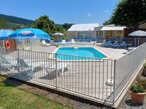 a fence around a swimming pool with chairs and umbrellas at Mobil-home pour 4 pers avec terrasse - API-1-52-494 in Langogne