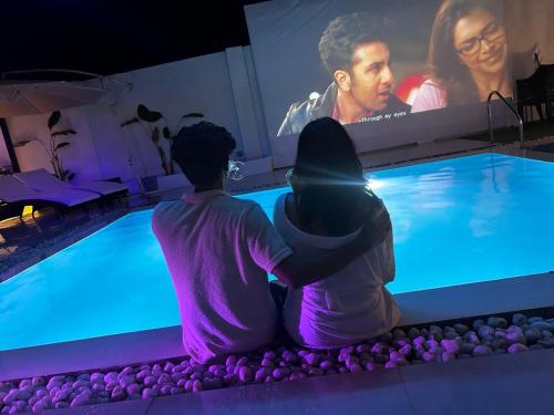 two people sitting in front of a swimming pool at White Tiger Villa in Madgaon