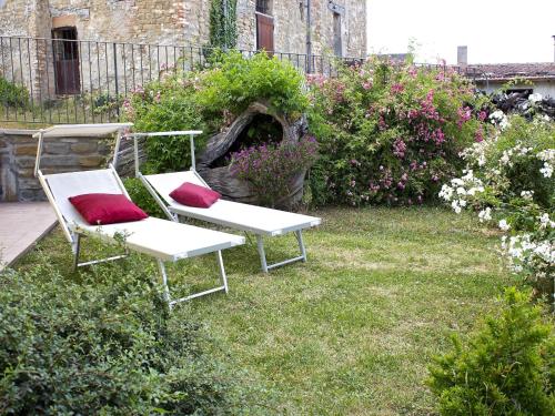 two white chairs with red pillows sitting in the grass at Stay with Balcony Views in Sassoleone