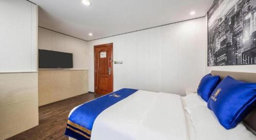 a bedroom with a bed with blue pillows and a tv at Super 8 Hotel Xiamen Railway Station in Xiamen