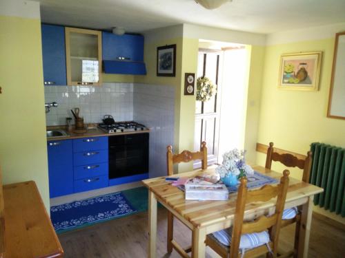 una cucina con tavolo in legno e armadi blu di Casa Walter- VDA-LA THUILE- CIR 0024 a La Thuile