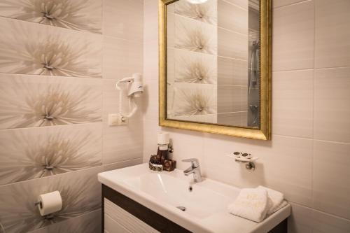 a white bathroom with a sink and a mirror at De Volan Boutique Hotel in Odesa