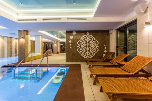 a pool in a hotel with chairs and a swimming pool at New Splendid Hotel & Spa - Adults Only (+16) in Mamaia