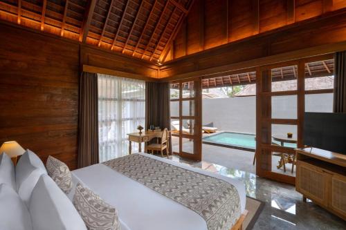 a bedroom with a bed and a television and a table at Unagi Wooden Villas by Emana in Ubud
