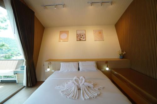 a bedroom with a bed with a bow on it at บ้านผูกรัก ทะเลหมอก ณ เขาค้อ in Khao Kho
