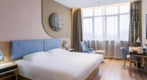 a bedroom with a large white bed and a desk at Home Inn Neo Zhuji Zhejiang Agriculture and Forestry University in Shaoxing