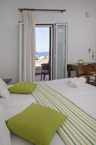 a bedroom with a bed with green sheets and a window at Parathyro Sto Aigaio 1 in Tinos