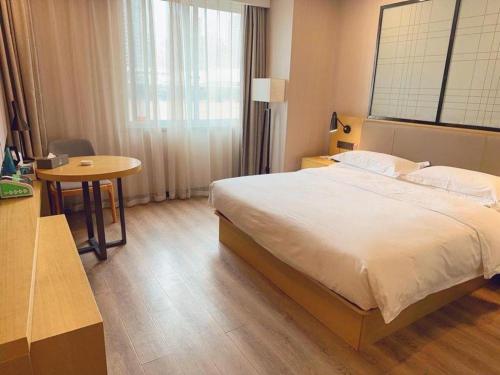 a bedroom with a large bed and a table at Echarm Hotel Yingshang High-speed Railway Station Wuzhou Wanhui Plaza in Fuyang