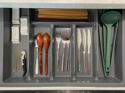 a drawer filled with utensils and forks and knives at Hongdae Station Link House with Massage Chair in Seoul