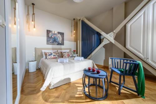 una camera con un letto bianco e una sedia blu di Candia Suites & Rooms a Heraklion