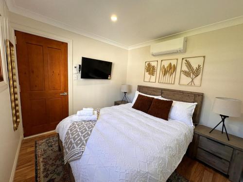 a bedroom with a bed and a tv on the wall at 4BR Home 10 mins walk to UOW, free parking, Wi-Fi, AC in Keiraville