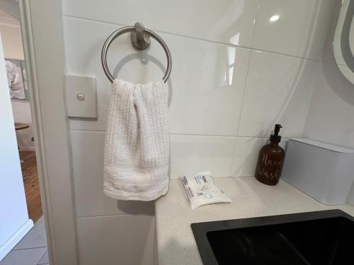 a white towel hanging on a wall in a bathroom at 4BR Home 10 mins walk to UOW, free parking, Wi-Fi, AC in Keiraville