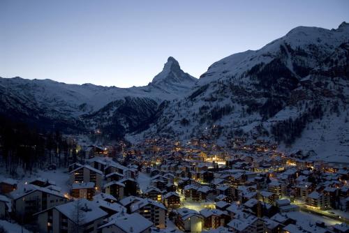 a town in the snow with mountains in the background at Hotel Garni Testa Grigia in Zermatt