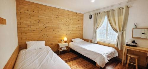 two beds in a room with a wooden wall at 너랑나랑 게스트하우스 in Seogwipo
