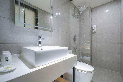 a white bathroom with a sink and a toilet at Green Tree Inn Urumqi San'gong Metro Station Exit in Ürümqi