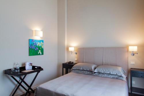 a bedroom with a bed and a nightstand with two lamps at Réva Resort in Monforte dʼAlba