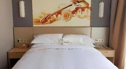 a bedroom with a white bed with a painting on the wall at Vienna Hotel Jiangsu Zhangjiagang Passenger Terminal Station in Zhangjiagang