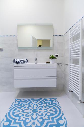 a bathroom with a sink and a mirror and a rug at B&B Villa Fanizza in Porto Cesareo
