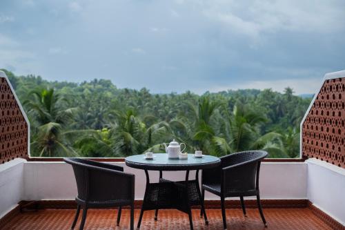 a table and chairs on a balcony with a view at The Raviz Kadavu, Kozhikode in Kozhikode