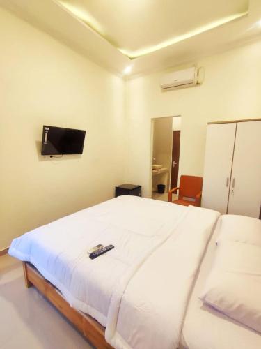 a bedroom with a white bed with a tv on the wall at Anymor Homestay in Komodo Labuan Bajo Airport