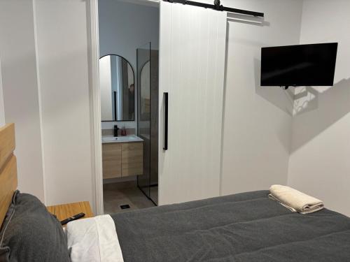 a bedroom with a bed and a bathroom with a mirror at Twin Ensuite Lux CBD apartment in Broken Hill