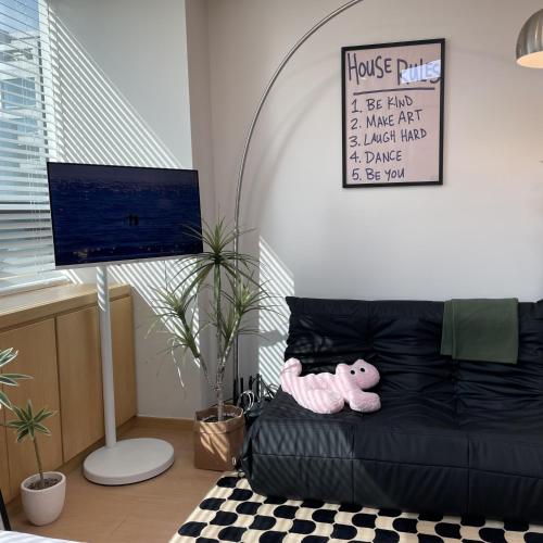 a room with a black couch with a pink teddy bear at Hongdae Station Link House with Massage Chair in Seoul