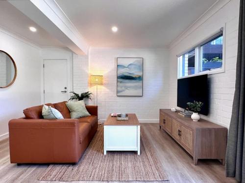 a living room with a couch and a tv at Elanora Escape- Hillside Retreat in Warriewood