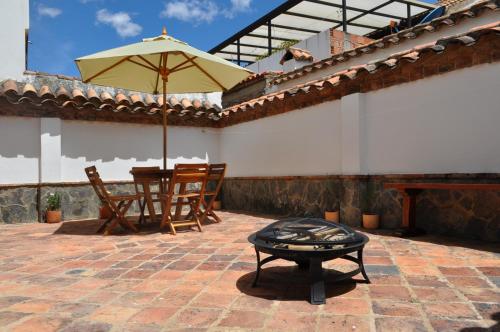 a patio with an umbrella and a table and a grill at Casa Rosita Cerca a Plaza Mayor in Villa de Leyva