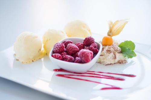 a plate with a bowl of raspberries and ice cream at Hotel Zur Burg GmbH in Burg Stargard