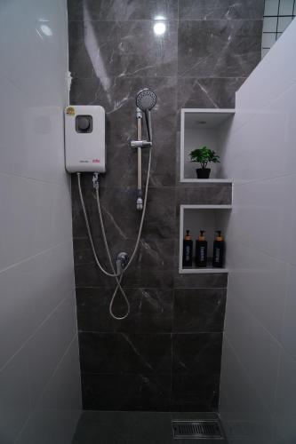 a shower in a bathroom with a black tile wall at บ้านผูกรัก ทะเลหมอก ณ เขาค้อ in Khao Kho