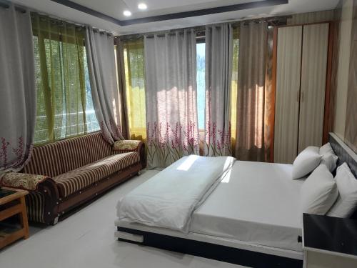 a bedroom with a bed and a couch and windows at Pacific Guest House Skardu in Skardu