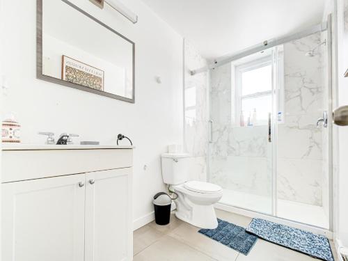 a white bathroom with a shower and a toilet at Chic & spacieux 2 chambres à Griffintown in Montréal