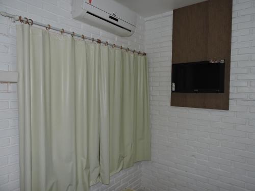 a bathroom with a shower curtain and a tv at Pousada Don Alberto's in Florianópolis