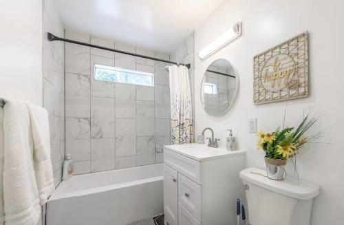 a white bathroom with a tub and a toilet and a sink at Central San Diego 2 BED Condo in San Diego