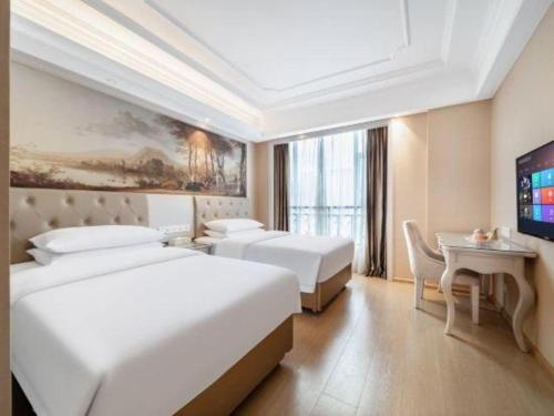 a hotel room with two beds and a television at Vienna Hotel Guiyang Jiaxiulou Jichang Road in Guiyang