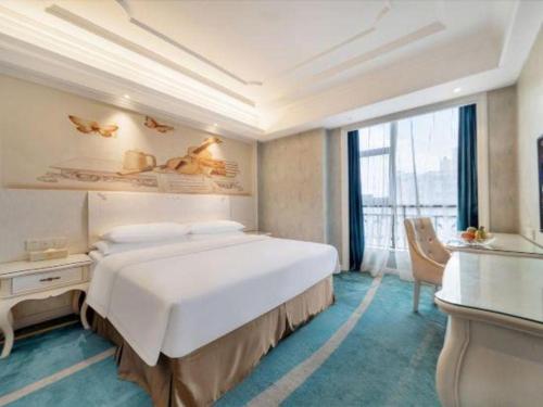a bedroom with a large white bed and a desk at Vienna Hotel Guiyang Jiaxiulou Jichang Road in Guiyang