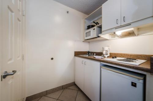a small kitchen with white cabinets and a sink at Tampa Bay Extended Stay Hotel in Largo
