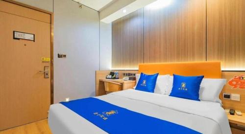 a bedroom with a large bed with blue pillows at IU Hotel Chengdu High-Tech Zone Longhu Times Street in Chengdu