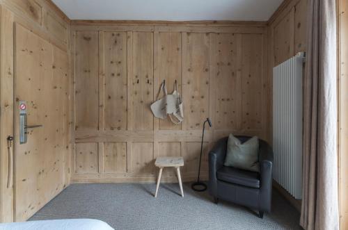 a bedroom with wooden walls and a chair and a lamp at Hotel ÜJA Scuol in Scuol