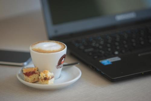 a cup of coffee and a plate of food next to a laptop at Buen Pastor Capuchinos in Cordoba