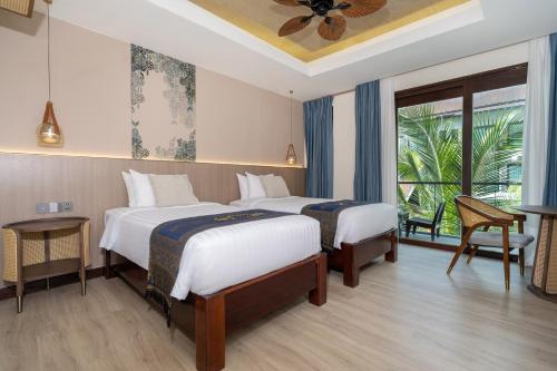 a hotel room with two beds and a balcony at Howard Johnson by Wyndham Phuket Naiyang in Thalang