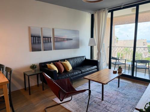 a living room with a black couch and a table at קיסריה נאות גולף- Oren Apartment in Caesarea