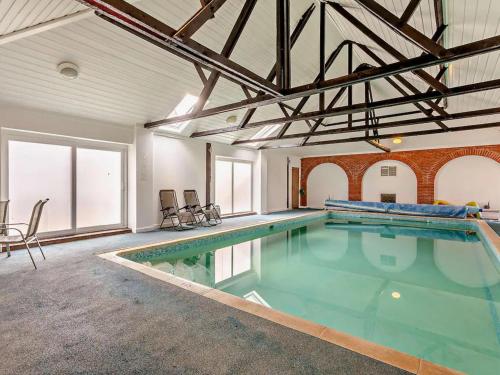 a large swimming pool in a large room with windows at Pond View Cottage - Uk48230 in Tibenham