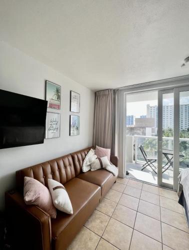 a living room with a brown couch and a balcony at Pet Friendly Studio Beach and Pool Access, gym ! in Sunny Isles Beach