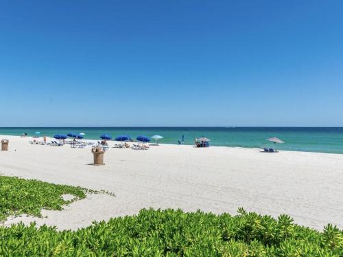 a beach with umbrellas and people sitting on the beach at Pet Friendly Studio Beach and Pool Access, gym ! in Sunny Isles Beach