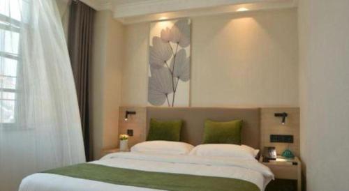 a bedroom with a large white bed with green pillows at GreenTree Inn Xuzhou High Speed Railway Station Express Hotel in Xuzhou