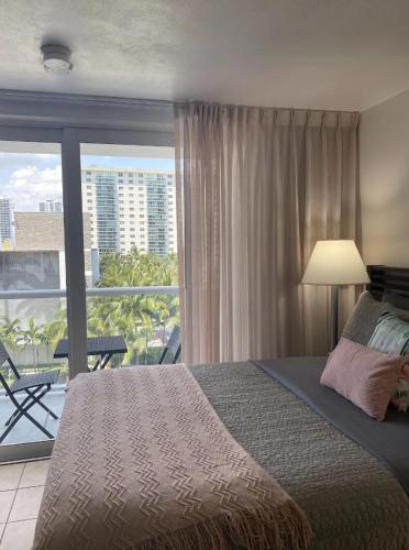 a bedroom with a bed and a view of a balcony at Pet Friendly Studio Beach and Pool Access, gym ! in Sunny Isles Beach